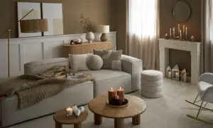 Przytulny salon w odcieniach sepia kolor. Miękki narożnik, drewniane stoliki, kominek z ozdobnymi świecami i ciepły pled tworzą atmosferę relaksu.