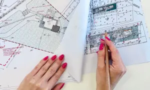 Ręce z różowym lakierem przeglądają mapę do celów projektowych, zaznaczając ołówkiem szczegóły.