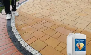 Osoba aplikuje preparat na kostkę brukową, tworząc efekt mokrej kostki. Widoczny kanister z produktem Nano-Bau.