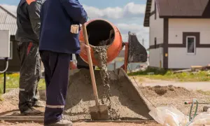 Robotnicy mieszają beton. Zastanawiasz się, ile kosztuje worek cementu na budowie?