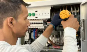 Elektryk pracuje przy panelu sterowania, unikając przeciążenia systemu.