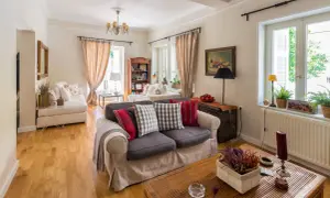 Przytulny salon w stylu angielskim z wygodnymi sofami, drewnianą podłogą i stylowymi dodatkami.