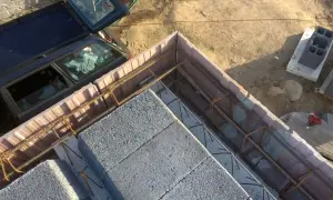 Szalowanie stropu z bloczków betonowych i zbrojenia. Obok stoi samochód.