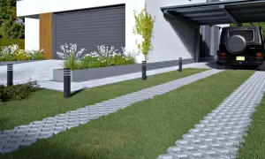 Nowoczesny podjazd z trawą i kostką brukową holland. Czarny SUV parkuje pod zadaszeniem.