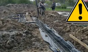 Budowa fundamentu: pracownicy wylewają beton do wykopu zbrojeniowego.