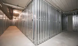 Korytarz z rzędami metalowych przegród tworzących komórki lokatorskie.