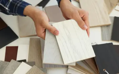Ręce trzymają próbki materiałów, w tym jasne płyty z widocznym usłojeniem, przypominające drewno. To może być mdf, co to za materiał?
