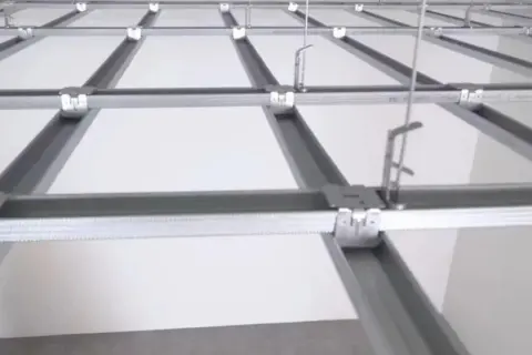 Sufit rastrowy z białymi panelami i metalową konstrukcją nośną, gotowy do montażu.