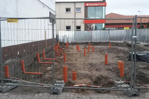 Budowa: widoczne pomarańczowe rury kanalizacyjne wystające z ziemi, przygotowanie pod instalację co.