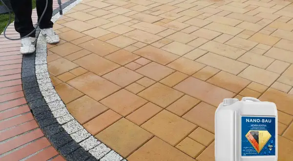 Osoba aplikuje preparat na kostkę brukową, tworząc efekt mokrej kostki. Widoczny kanister z produktem Nano-Bau.