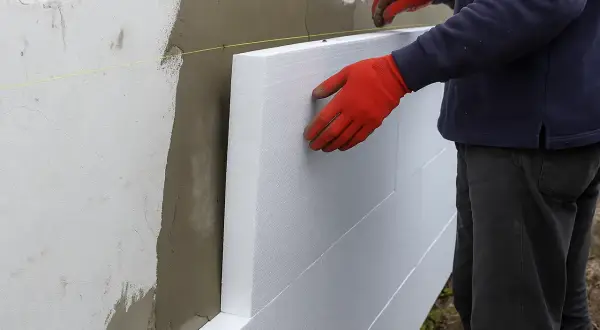 Pracownik w czerwonych rękawicach montuje płyty styropianowe. Poznaj cenę ocieplenia za 1m2 robocizna.