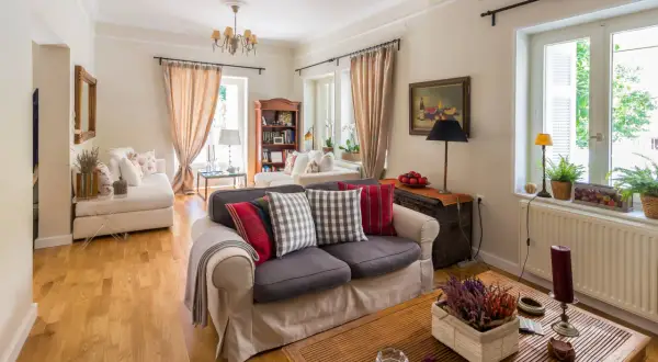 Przytulny salon w stylu angielskim z wygodnymi sofami, drewnianą podłogą i stylowymi dodatkami.