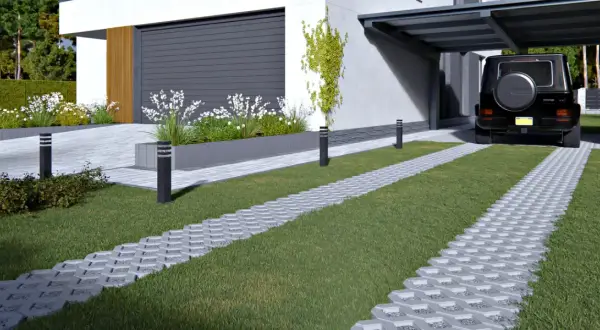 Nowoczesny podjazd z trawą i kostką brukową holland. Czarny SUV parkuje pod zadaszeniem.