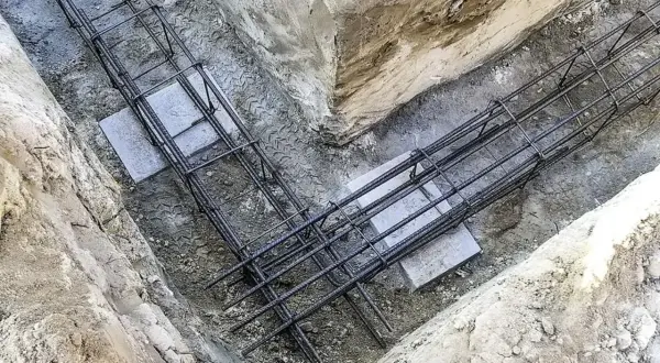 Gotowe zbrojenie fundamentów w wykopie. Stalowe pręty tworzą solidną konstrukcję, gotową na zalanie betonem.