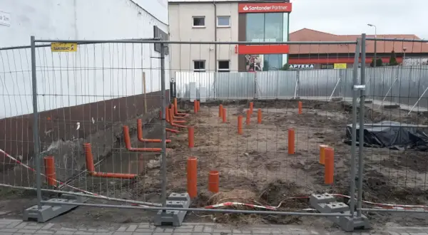 Budowa: widoczne pomarańczowe rury kanalizacyjne wystające z ziemi, przygotowanie pod instalację co.