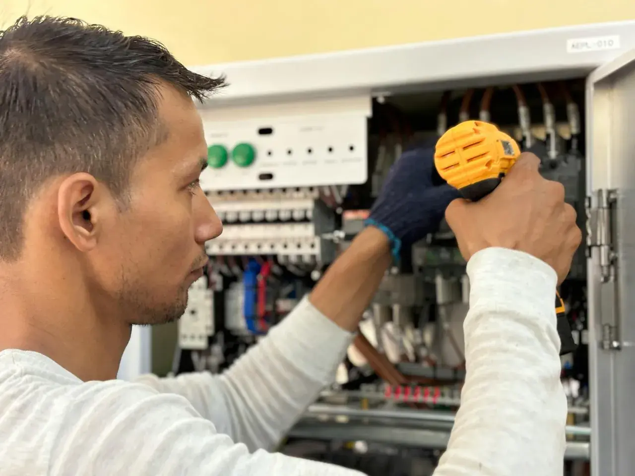 Elektryk pracuje przy panelu sterowania, unikając przeciążenia systemu.