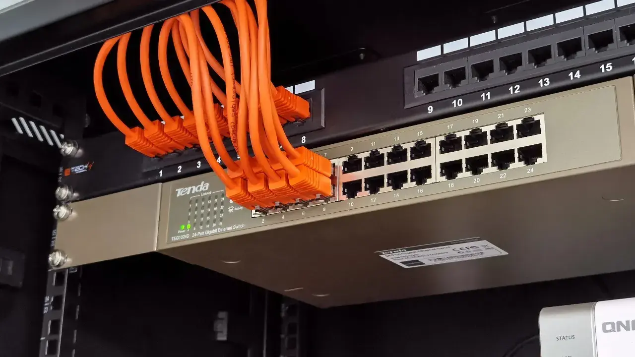Pomarańczowe kable sieciowe podłączone do przełącznika LAN.
