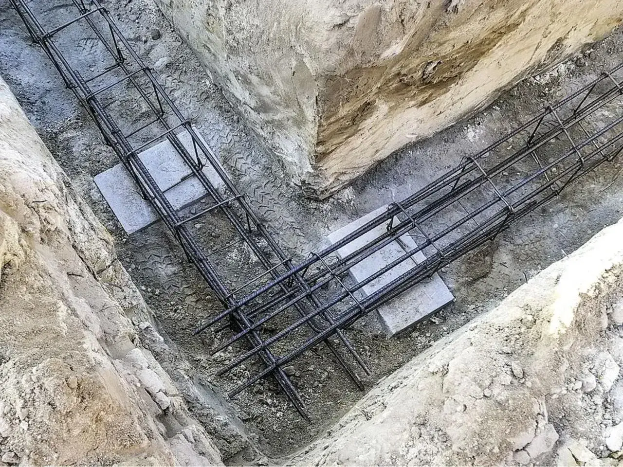 Gotowe zbrojenie fundamentów w wykopie. Stalowe pręty tworzą solidną konstrukcję, gotową na zalanie betonem.