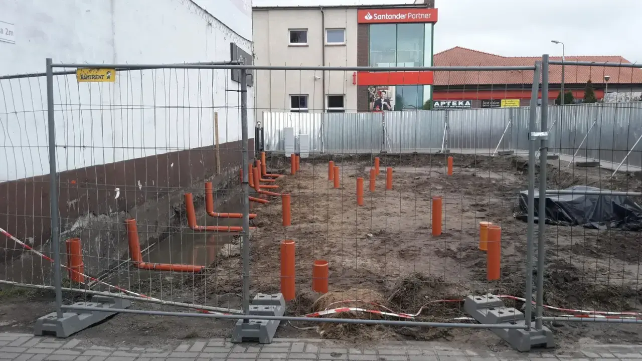 Budowa: widoczne pomarańczowe rury kanalizacyjne wystające z ziemi, przygotowanie pod instalację co.