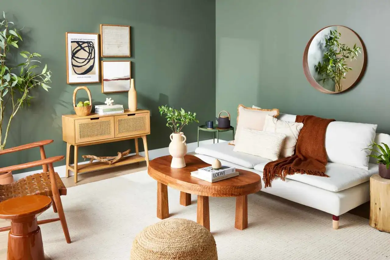 Salon w stylu boho z zielonymi ścianami, drewnianymi meblami i roślinami. Aranżacja sprzyja harmonii i relaksowi, zgodnie z zasadami feng shui.