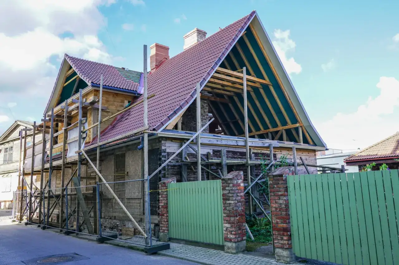 Remont starego domu od czego zacząć? Dom w trakcie prac, z rusztowaniem, nowym dachem i widoczną konstrukcją.