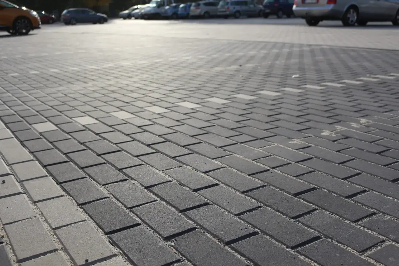 Szary parking z kostki brukowej holland, z samochodami w tle.