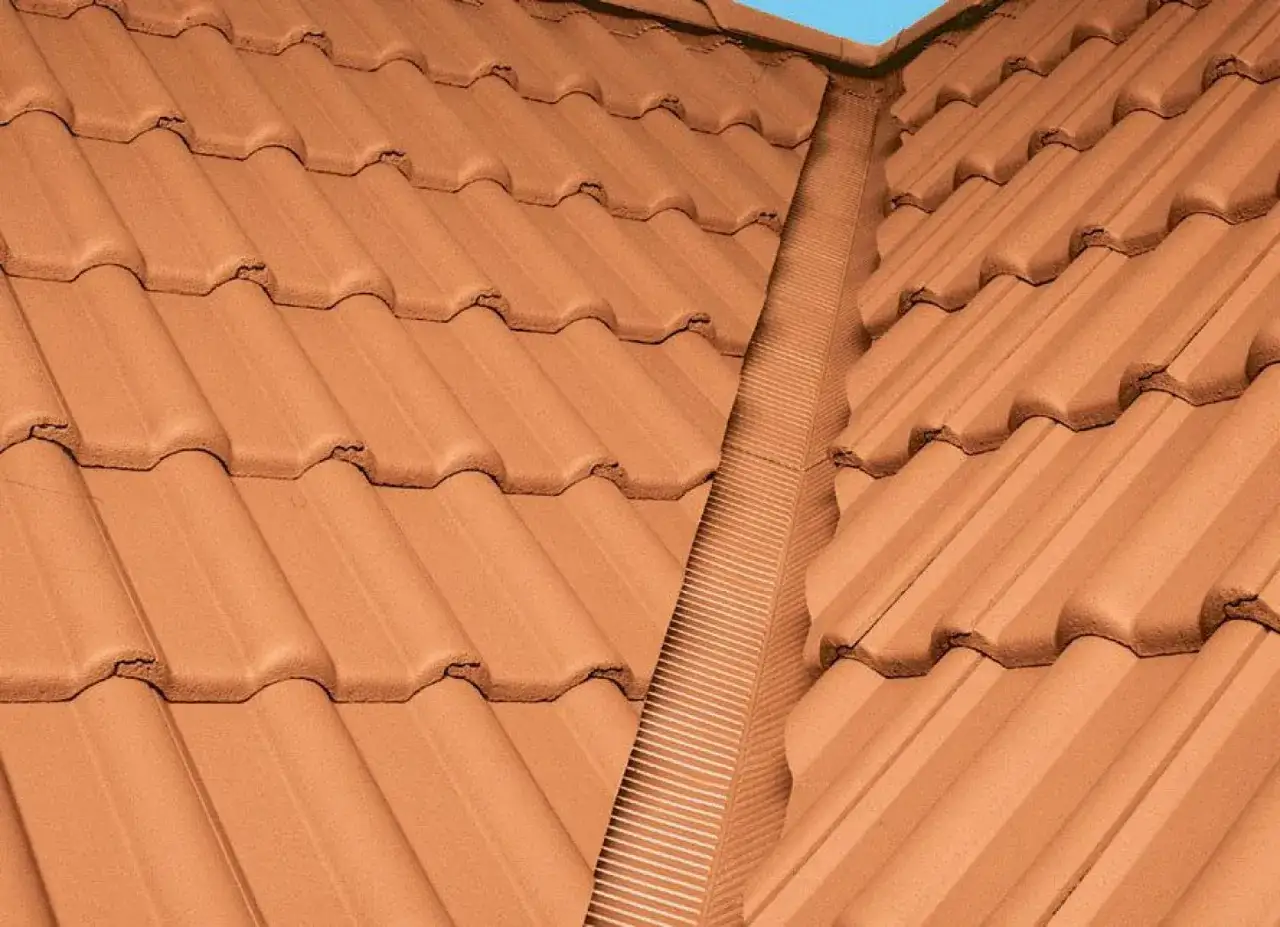 Brązowy dach wielospadowy z dachówki ceramicznej, z widocznym pasem wentylacyjnym w kalenicy.