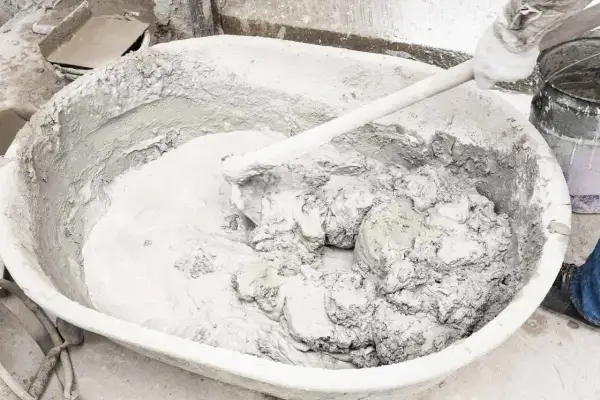 Mieszanie wapna gaszonego z wodą w dużej misie, tworząc gładką masę do prac budowlanych.